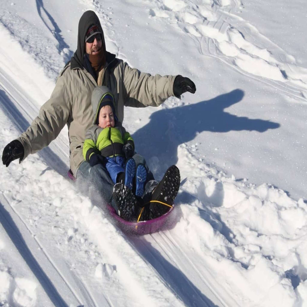 Man and child on snow sledge going down hill - showing a better life after beating burnout
