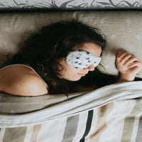 white woman laying in bed with an eye mask on. indicating difficulty sleeping.